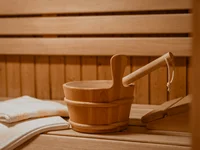 Ein Hotel in Großarl für Aktive | für Genießer | für dich Saunazubehör mit Holzeimer, Kelle und weißen Handtüchern in einer Sauna