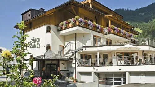 Ein Hotel in Großarl für Aktive | für Genießer | für dich Haus mit Balkonen und Blumen im Berggebiet bei sonnigem Wetter