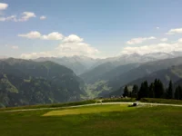 Ein Hotel in Großarl für Aktive | für Genießer | für dich Grüne Almwiese mit Blick auf Berge und bewölkten Himmel