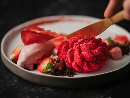 Ein Hotel in Großarl für Aktive | für Genießer | für dich Nahaufnahme von einem roten Dessert mit Erdbeere und Kuchenmesser