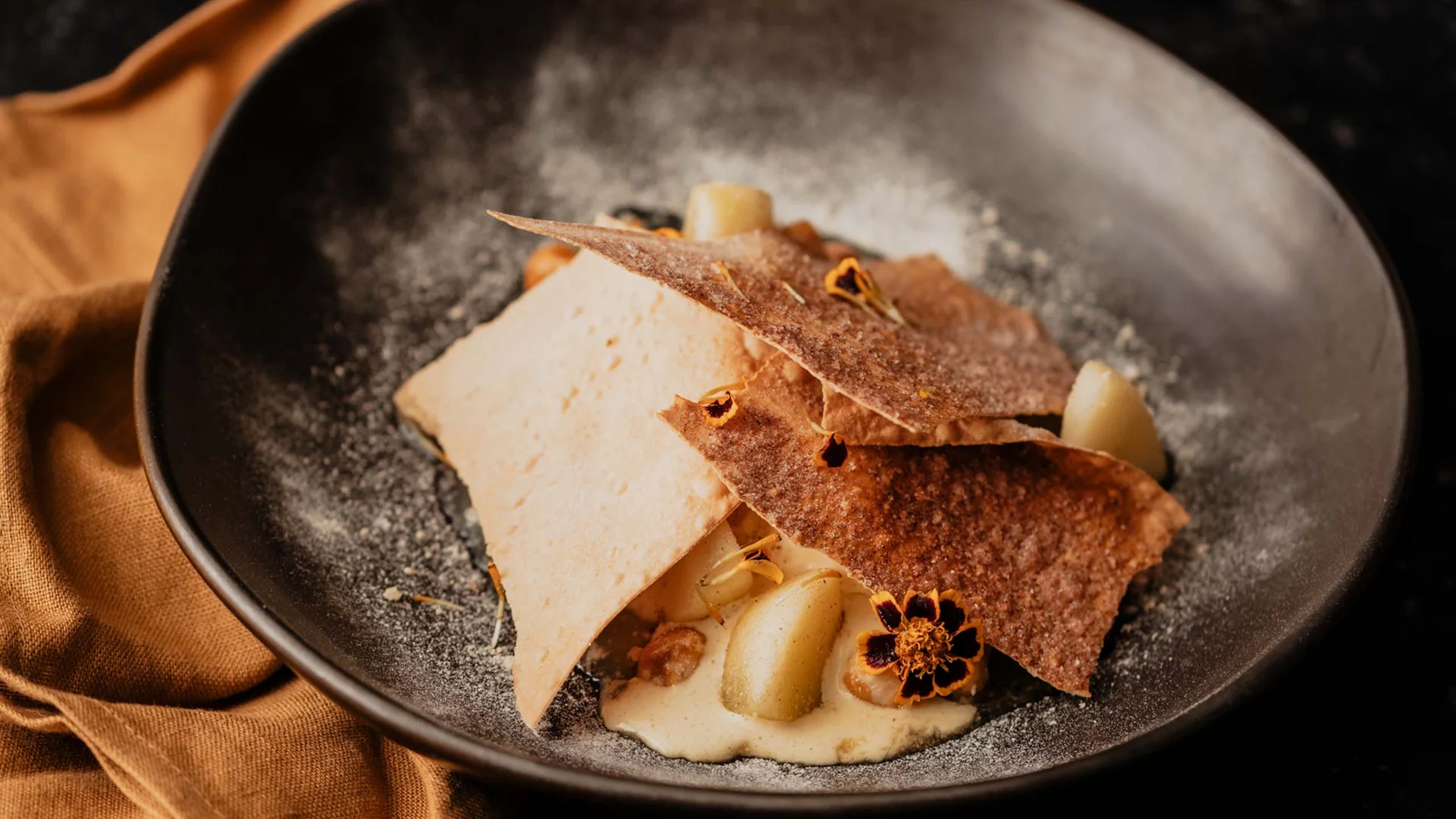 Ein Hotel in Großarl für Aktive | für Genießer | für dich Gourmet-Dessert auf schwarzem Teller mit goldfarbenem Besteck und Tasse Kaffee